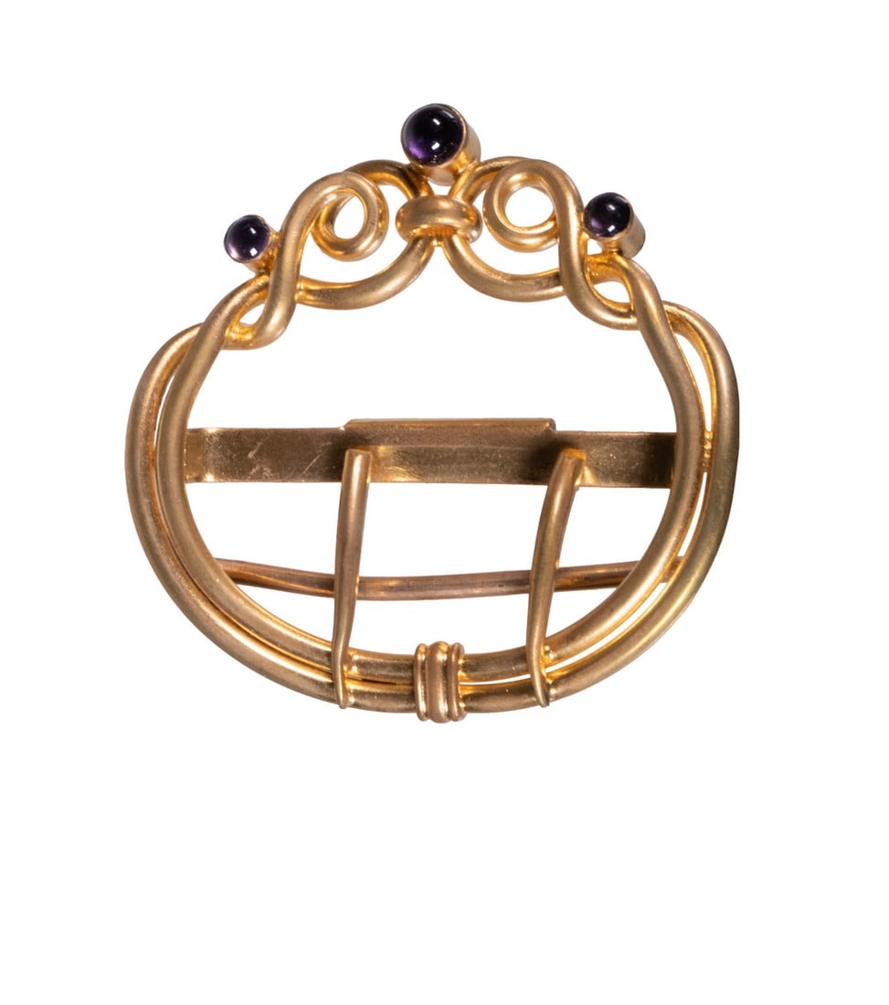ART NOUVEAU GILT METAL BELT BUCKLE: An Art Nouveau period belt buckle, of circular form with scrolling openwork design, decorated with three bezel-set purple glass cabochons. The surface finished in rich gilt, with flowing sinuous lines