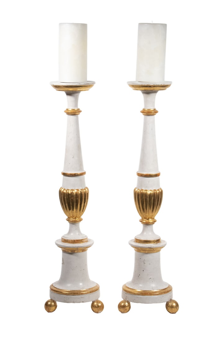 PR ITALIAN GILT AND PAINTED WOOD CANDLESTICKS WITH CANDLES: A pair of tall gilt and painted wood candlesticks, possibly Italian, in white and gold, each with turned baluster form, fluted gilt knop, and ball feet, topped with wax candles.Candlesticks: 24 1/2 x