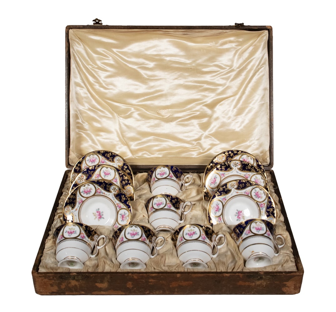 CROWN STAFFORDSHIRE PORCELAIN TEA SET RETAILED BY ALFRED B. PEARCE & CO., C. 1906–1915: A boxed six-piece tea set comprising six cups and saucers, total 12. Finely decorated in cobalt blue, gilt scrollwork, and hand-painted rose roundels. Each piece marked “Crown Staffordshire