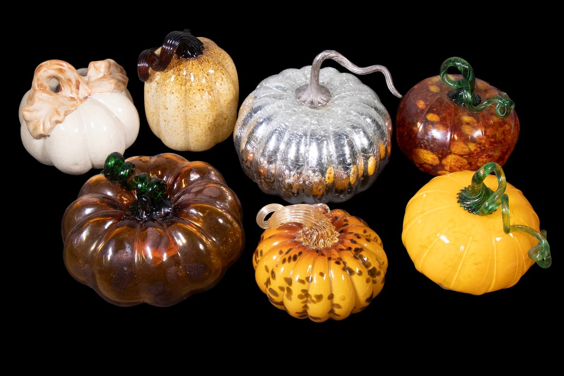 (7) GLASS AND STONEWARE PUMPKINS, IN THE STYLE OF ROBERT LAUNDREY: A group of seven decorative pumpkins, six executed in hand-blown glass and one in cream-glazed stoneware. The glass examples feature vibrant hues, curled green stems, and organic texturing, several