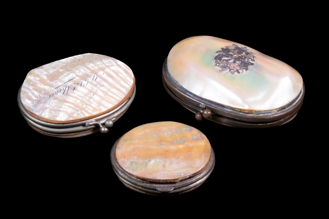(3) MOTHER-OF-PEARL SHELL COIN PURSES WITH SILK INTERIORS, 19TH CENTURY: A group of (3) hinged coin purses constructed from polished mother-of-pearl shells, each fitted with a metal clasp and lined with pleated silk compartments. One example bears a silver-tone floral