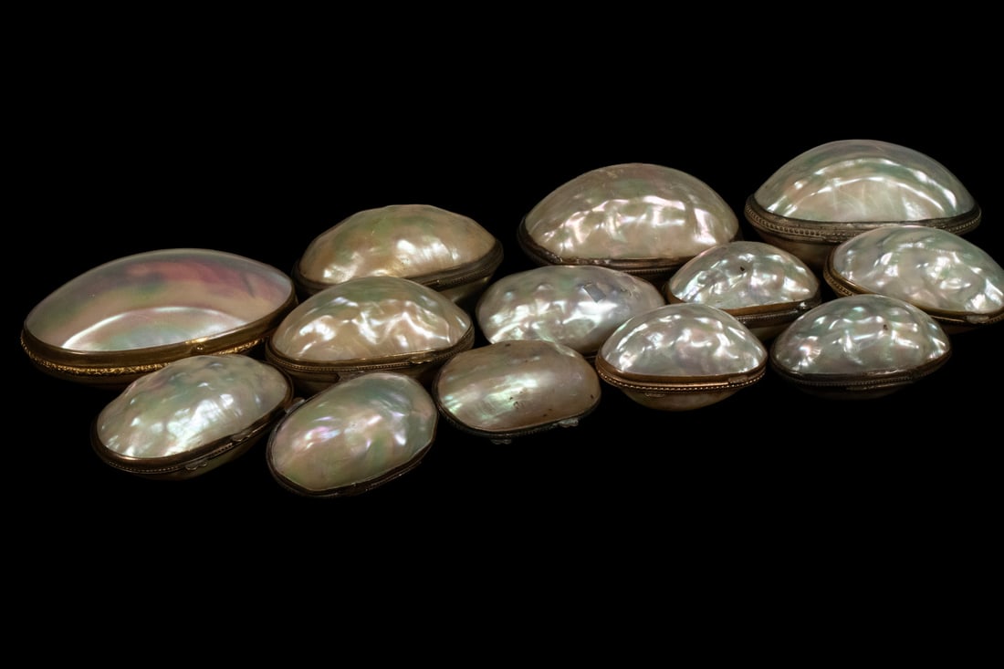 (13) MOTHER-OF-PEARL COIN PURSES OR SMALL BOXES: Comprising thirteen (13) small oval purses or boxes made from polished mother-of-pearl halves with metal hinges and frames. Two feature decorative bezels, one with delicate engraved borders. All