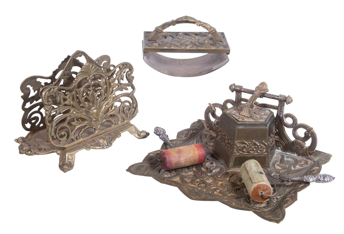 (5PC) VICTORIAN BRASS DESK ACCESSORIES: A group of ornate brass desktop accessories including a heavily embossed brass inkwell stand with hinged lid and matching rocker blotter, together with an openwork brass letter rack, accompanied by