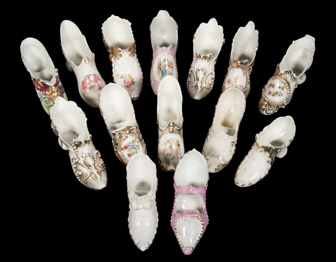 (14) CONTINENTAL PORCELAIN SHOE FIGURINES, EARLY TO MID-20TH C.: Decorated in various Rococo and Victorian revival styles with applied floral relief, transfer prints of romantic figures, and gilt accents. All in high-heeled forms and hand-decorated, likely made