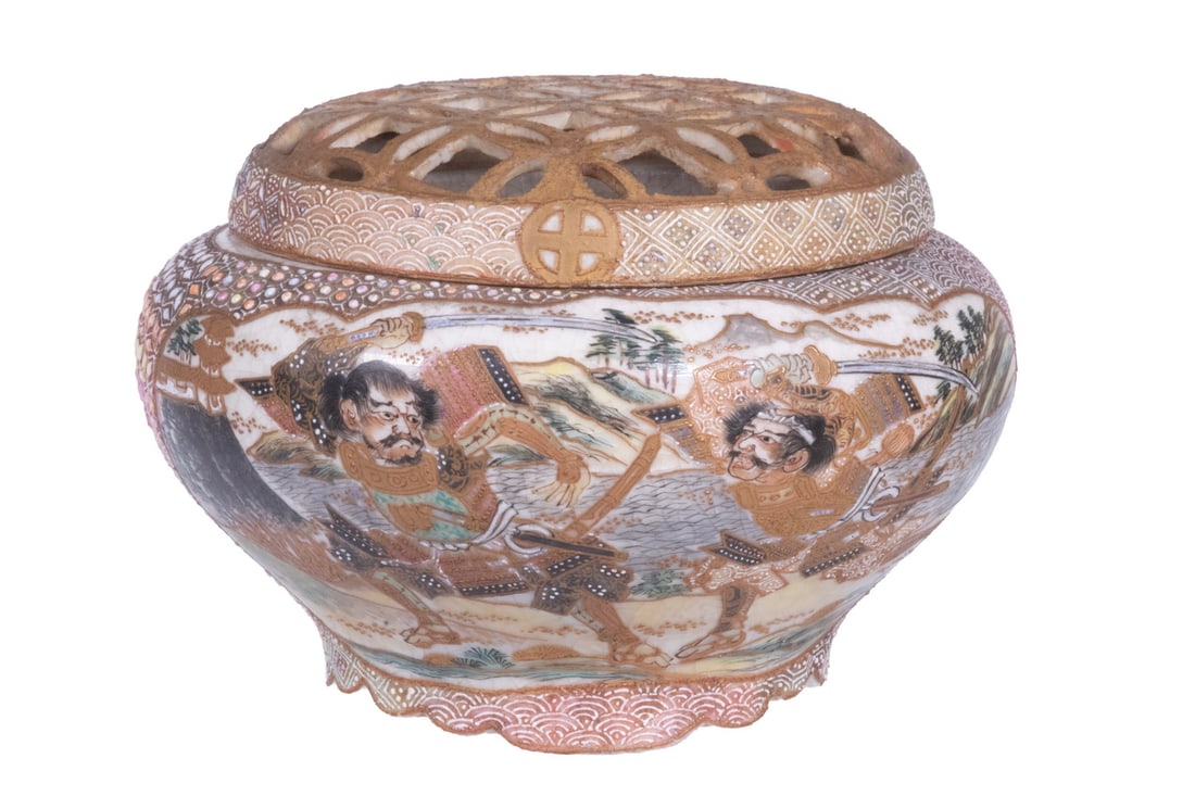 JAPANESE SATSUMA INCENSE BURNER WITH PIERCED COVER, MEIJI PERIOD: A Japanese Satsuma earthenware incense burner with a reticulated domed cover, resting on a short foot. The body is finely painted with Buddhist scenes, reserved against patterned grounds with extensiv