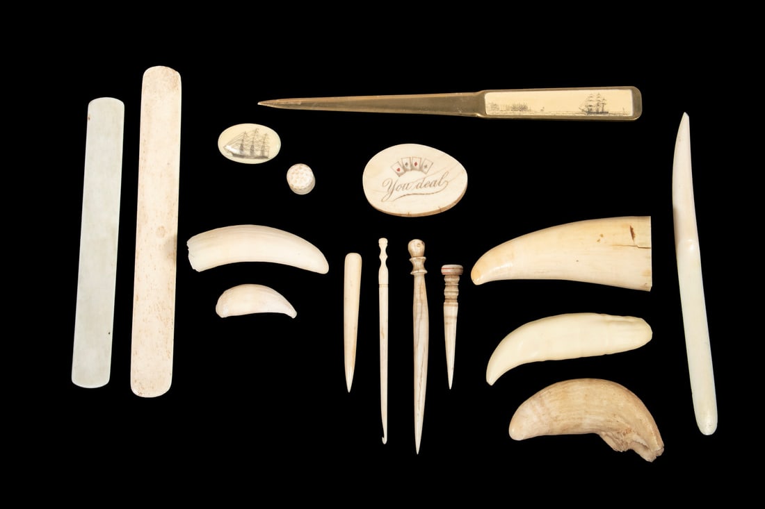 (16 PCS) WHALE IVORY TEETH AND CARVINGS: Including: Brass letter opener with scrimshaw of ships, "You Deal, Jackpot" poker chip, Scrimshaw Pin of Ship, (5) Fids, (2) Busks, Thimble, (5) Raw Teeth.Lrg: 9 1/4 x 7/8 in. (23.5 x 2.2 cm.), sml: