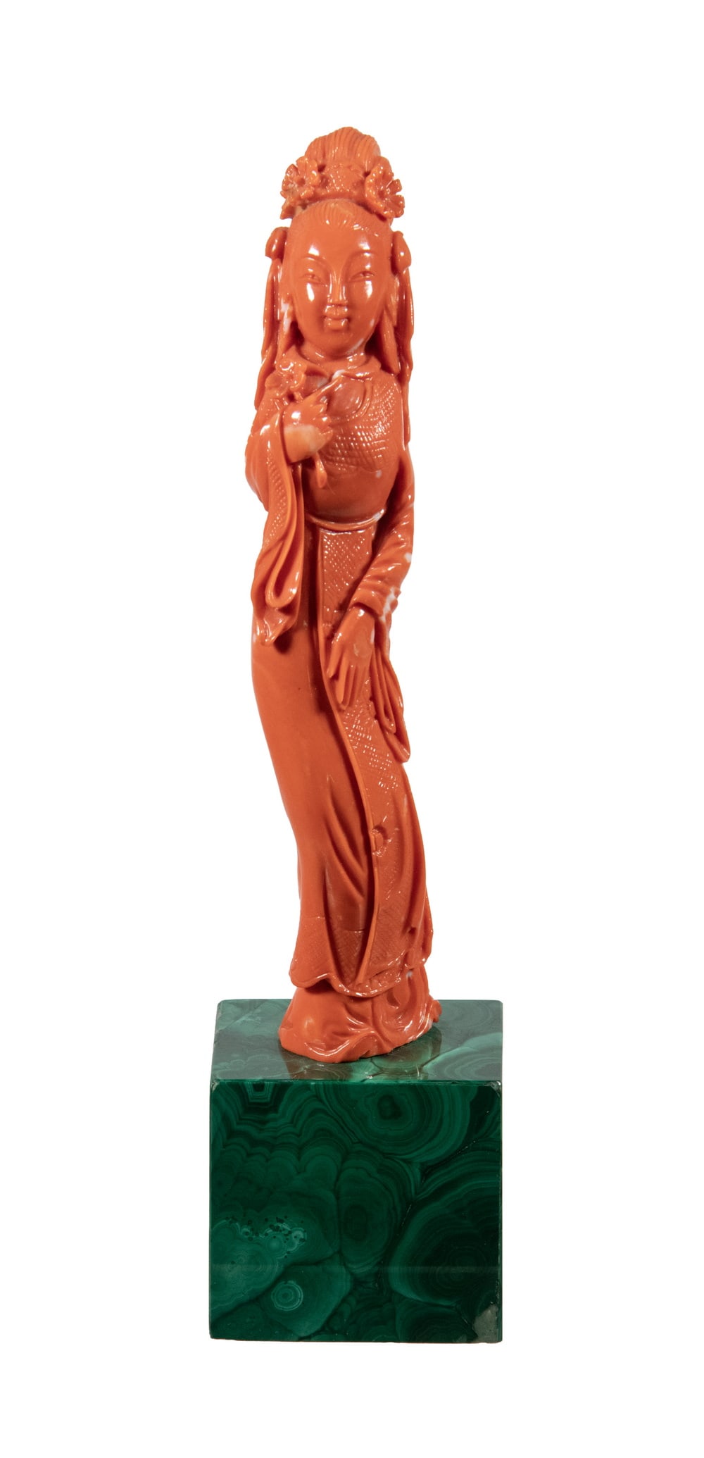 CHINESE CARVED CORAL FIGURE ON A MALACHITE STAND, 20TH CENTURY: A finely carved coral figure depicting an elegant lady holding a blossom, shown in flowing robes with detailed coiffure and floral ornaments. Warm reddish-orange coral with natural lighter