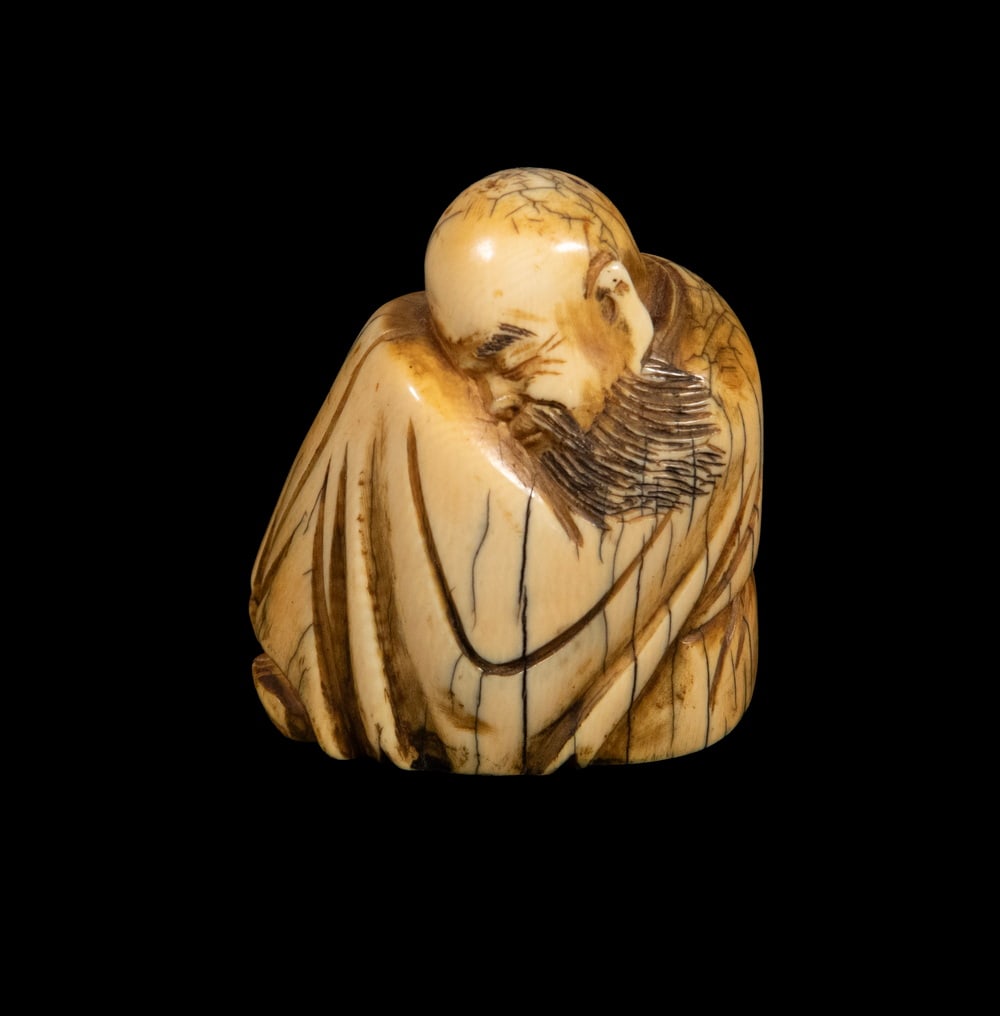 CHINESE IVORY FIGURAL CARVING WITH MARK, 19TH CENTURY: A small ivory carving of a robed elder with inked incised details. Underside bears an apocryphal "Qianlong Nian Zhi" mark.2 1/4 x 2 x 1 5/8 in. (5.7 x 5.1 x 4.1 cm.)