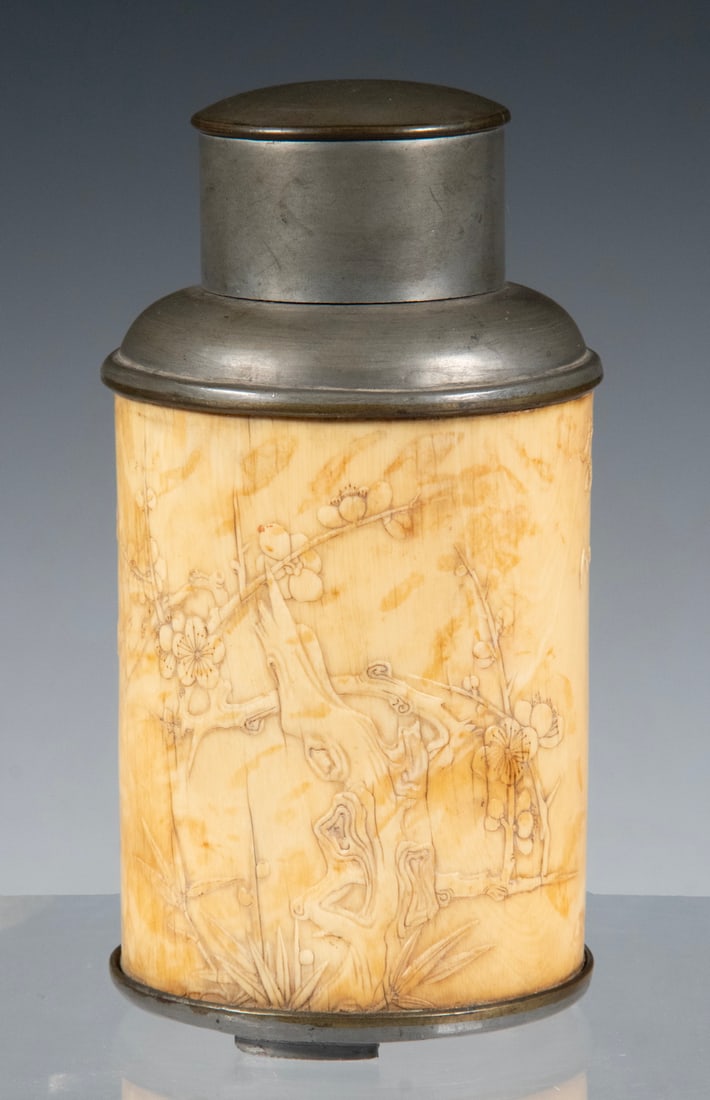 CHINESE CARVED IVORY PEWTER TEA CANISTER, LATE QING TO EARLY REPUBLIC PERIOD: A cylindrical Chinese tea canister carved from ivory, decorated in low relief with prunus blossoms, bamboo leaves, and incised calligraphy. Fitted with a pewter liner and lid produced using