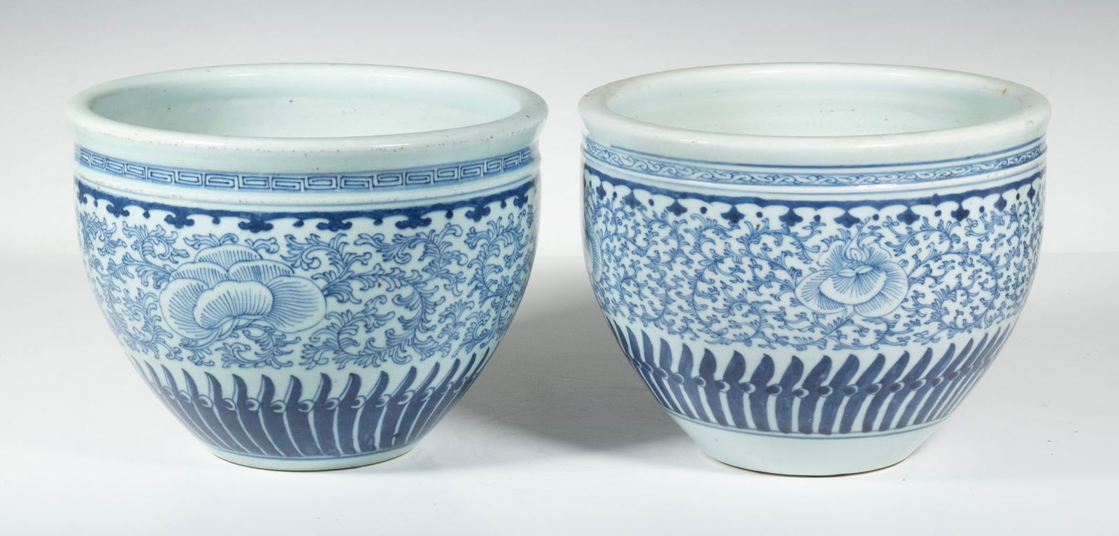 PR CHINESE BLUE AND WHITE PORCELAIN JARDINIERES, LATE QING PERIOD: Each of the bulbous forms with a rolled rim, finely painted with scrolling foliage and stylized lotus lappets around the base, the interior glazed and base unmarked.Each: 7 1/4" x 9 3/4" diam.