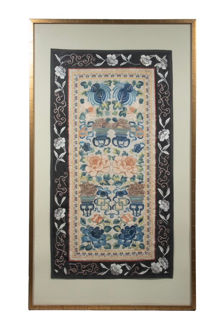 CHINESE FORBIDDEN STITCH FLORAL EMBROIDERED SILK PANEL, 19TH CENTURY: A vertically oriented Chinese embroidered silk panel depicting auspicious floral offerings arranged in ritual vessels, framed by scrolling foliage and decorative borders. Executed in silk floss with e
