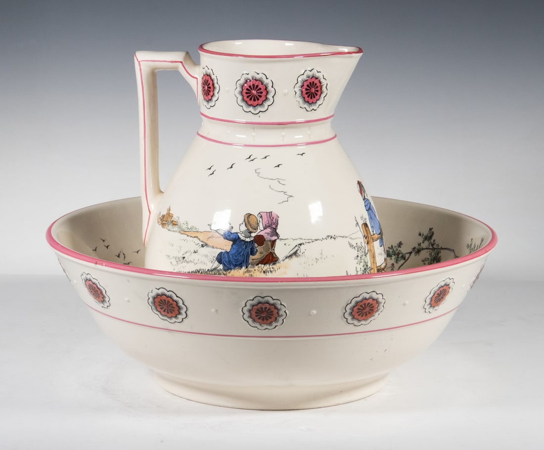 KATE GREENAWAY “PASTIMES” WASH JUG AND BASIN: A Victorian earthenware wash jug and matching basin from Brownfield & Sons, decorated with transfer-printed and hand-colored rural child figures by Kate Greenaway, within molded and enamel-highlighted
