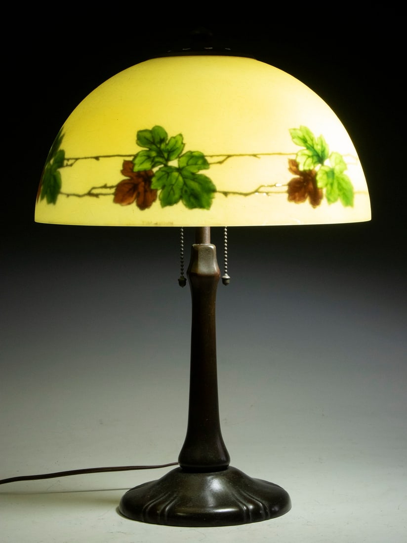 HANDEL LAMP WITH REVERSE PAINTED GLASS SHADE: Early 20th c. Handel Reverse Painted Yellow Mosserine Glass Shade, with leaf decoration, signed "Handel 6584"; atop a patinated metal lamp base, unsigned but probably by Handel. Slender shape with