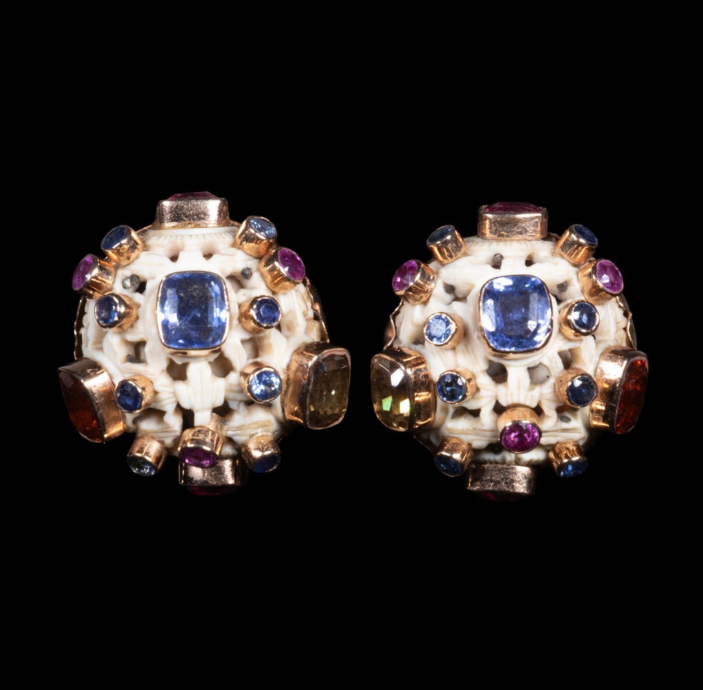 PR FULCO DI VERDURA 14K GOLD, MULTIGEM & IVORY EAR CLIPS, C. 1930S: A pair of circular ear clips each centered with a faceted blue sapphire and further set with tourmalines, rubies, and citrines of various cuts in 14K yellow gold mounts. The carved ivory ground provid