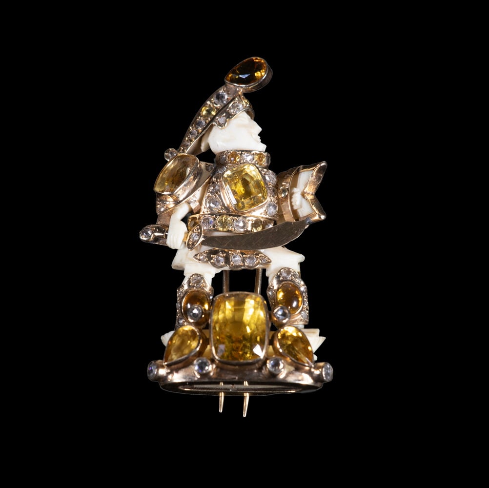 FULCO DI VERDURA 14K GOLD, YELLOW SAPPHIRE, CITRINE & DIAMOND FIGURAL BROOCH: A finely crafted figural brooch depicting a standing warrior, the carved ivory head and body mounted in 14K yellow gold armor set with cushion-cut yellow sapphires, pear-shaped citrines, and accent di