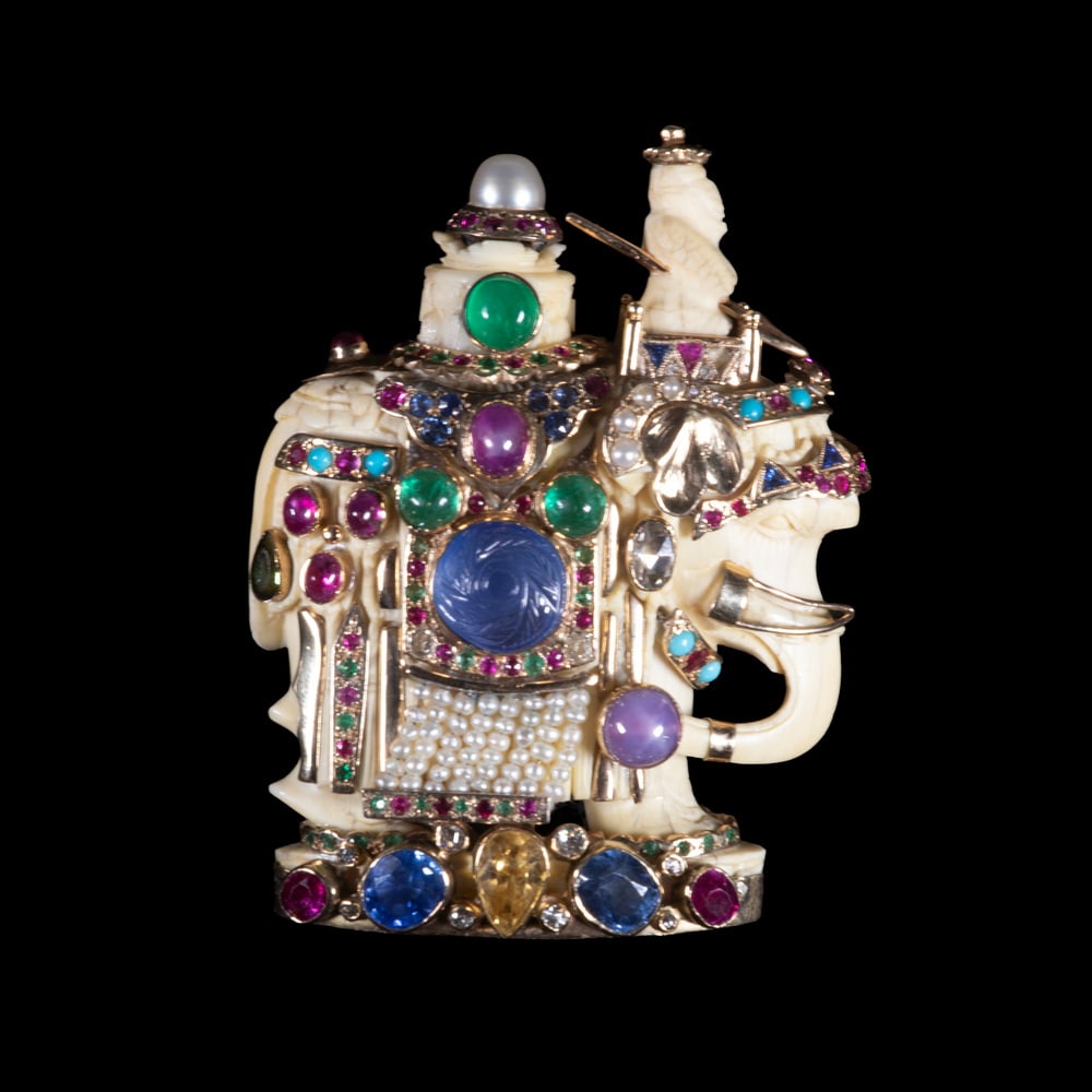 FULCO DI VERDURA 14K GOLD, MULTI-GEM AND IVORY FIGURAL BROOCH, C. 1930S: An elaborate figural brooch depicting a carved ivory rider seated on an elephant, the 14K yellow gold structure set with multi-colored sapphires, rubies, emeralds, diamonds, turquoise, tourmaline, and