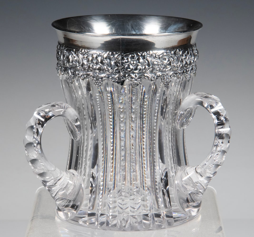 CUT CRYSTAL LOVING CUP WITH STERLING SILVER RIM: Circa 1900 American Brilliant Cut Glass Three Handled Cup, with floral decorated sterling silver rim marked "Sterling 925/1000."OS: 6 x 6 1/2 x 6 1/2 in. (15.2 x 16.5 x 16.5 cm.)