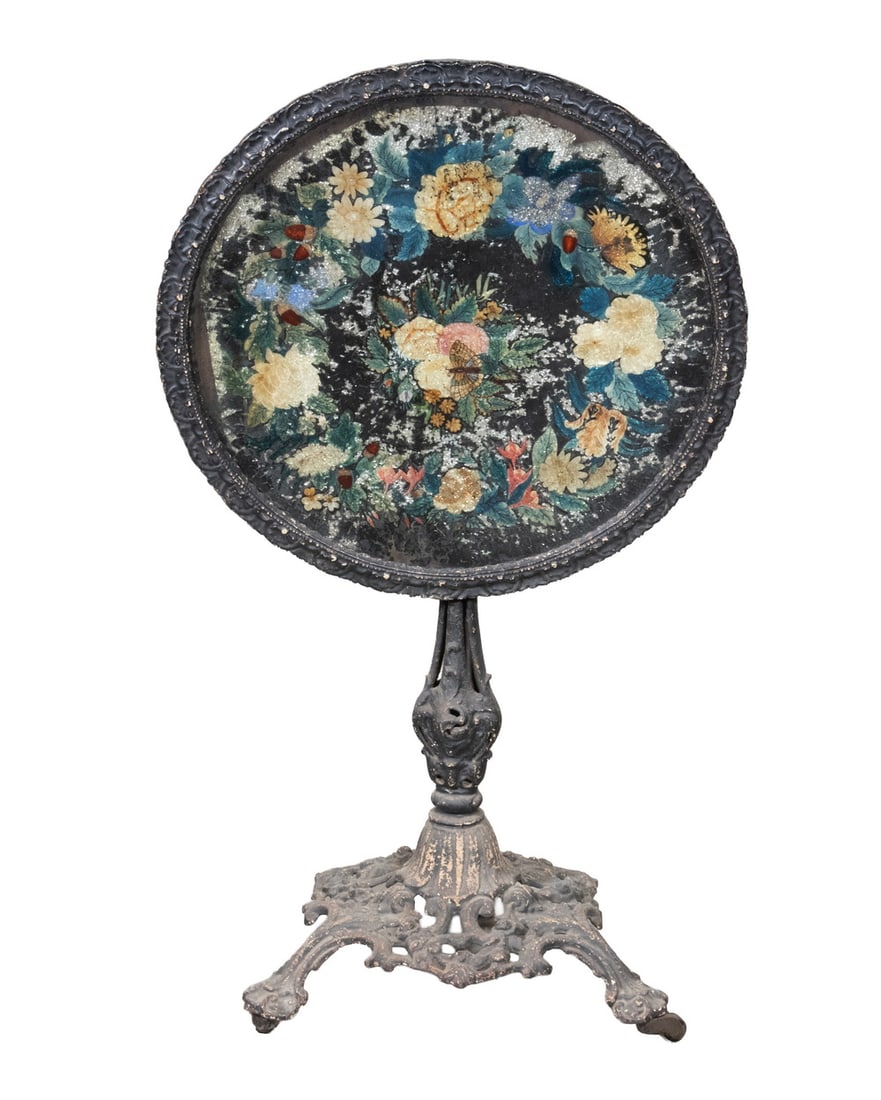 VICTORIAN TILT-TOP CAST IRON PARLOR TABLE: 19th c. Round Table, with glass-covered floral and butterfly painted top with foil highlights, paper mache edge, set on a cast iron base with turned pedestal and pierced base, with casters. 39 1/2" hi