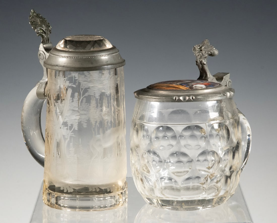 (2) PEWTER MOUNTED GLASS STEINS: (2) PEWTER MOUNTED GLASS STEINSLot of (2) Vintage Steins, incl: German 0.5-Liter vessel with bullseye molded body, lid with pine cone design thumb-lift and battle scene decoration, interior engraved "