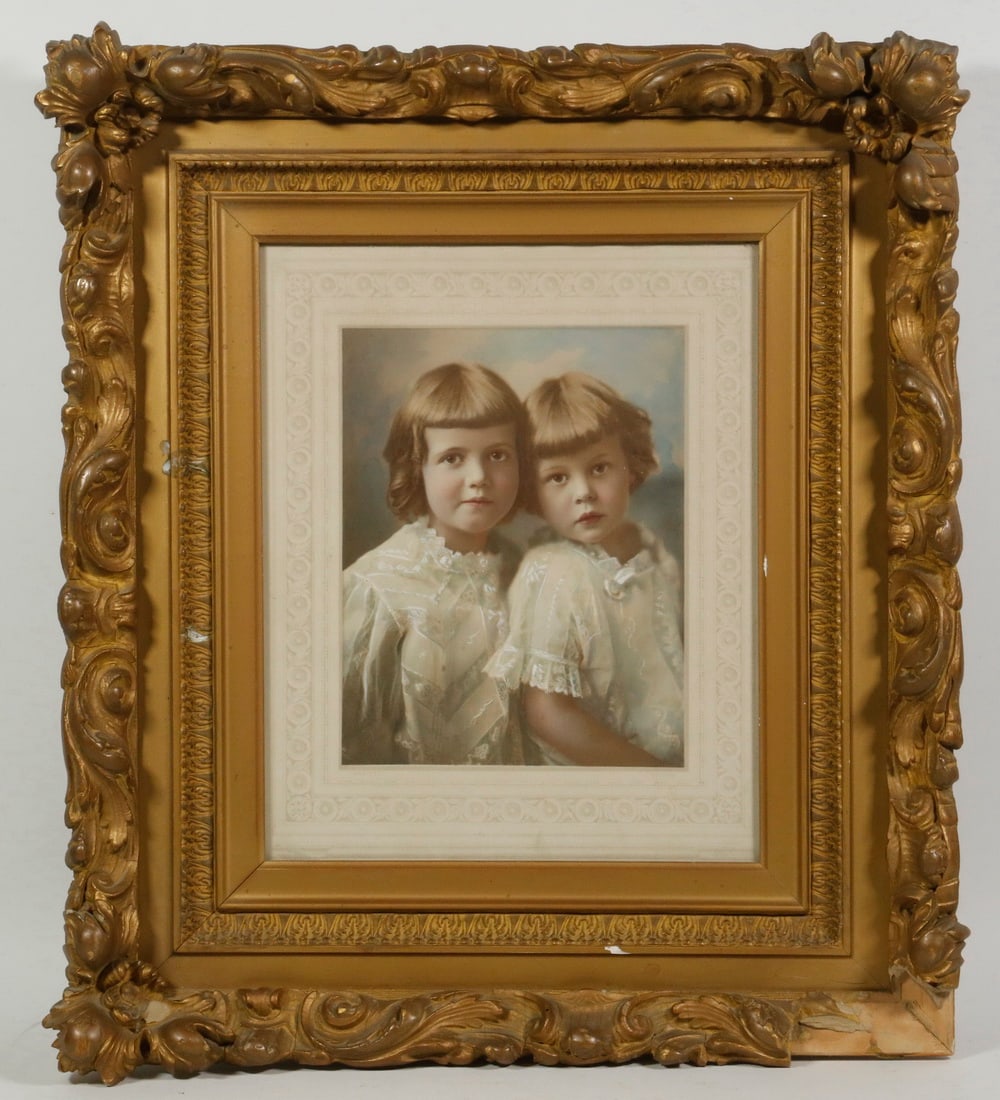 FRAMED HAND COLORED PHOTOGRAPH, CIRCA 1915: FRAMED HAND COLORED PHOTOGRAPH, CIRCA 1915 Portrait of Two Blonde Sisters, in an ornate gold gesso frame, under decorated mat and non-glare glass. One frame corner gone. OS: 19 1/2" x 16 1/2", SS: 8