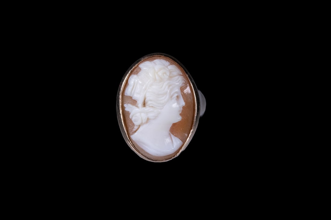 VINTAGE 14K GOLD SHELL CAMEO RING: VINTAGE 14K GOLD SHELL CAMEO RINGA 14K yellow gold ring set with an oval shell cameo carved in profile, depicting a classical female figure. The cameo is bezel-set within a polished gold mount with so