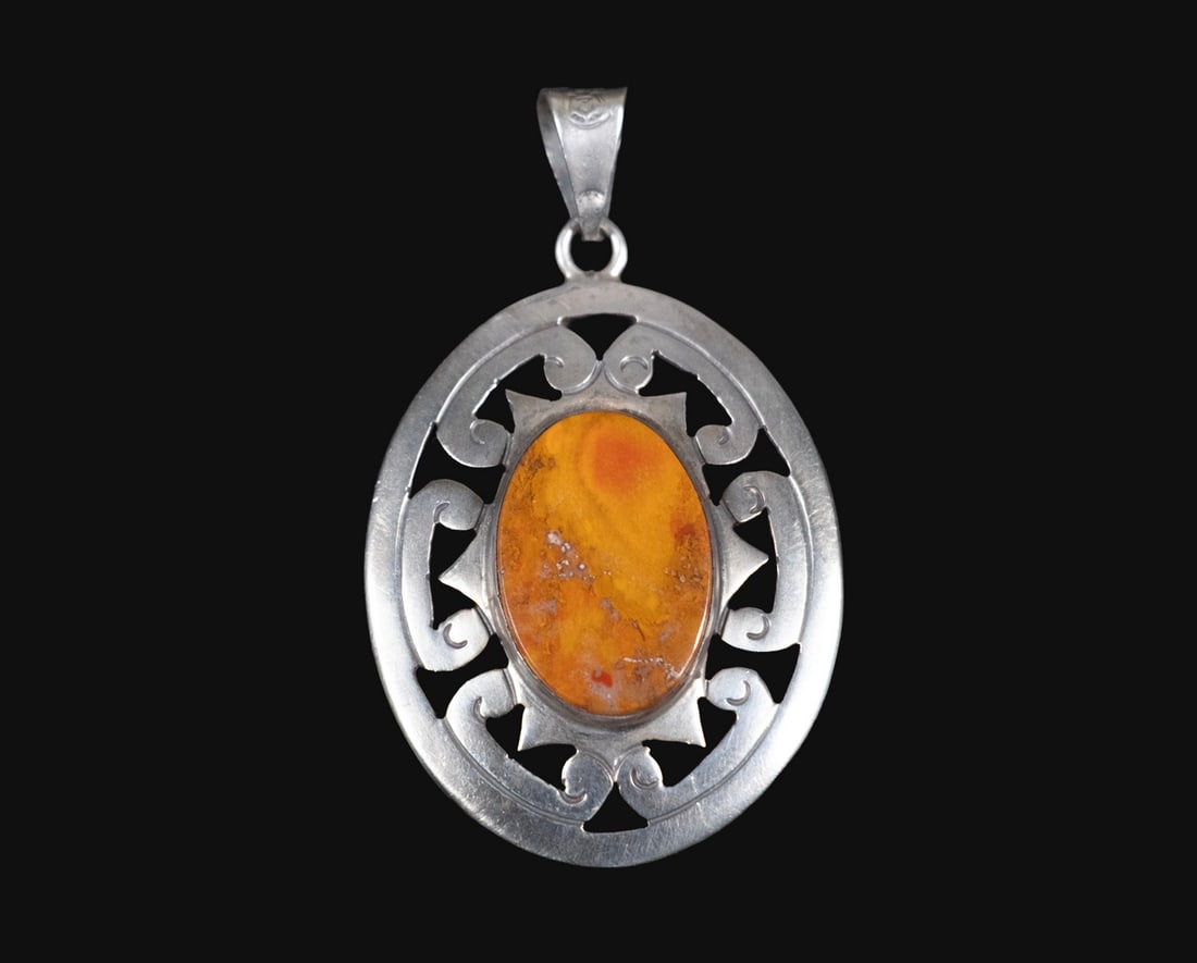 MEXICAN STERLING SILVER AGATE PENDANT: MEXICAN STERLING SILVER AGATE PENDANTA sterling silver pendant set with an oval dendritic agate cabochon of warm yellow and orange tones, within a pierced scrollwork frame. Stamped 'MEXICO 925 STERLIN