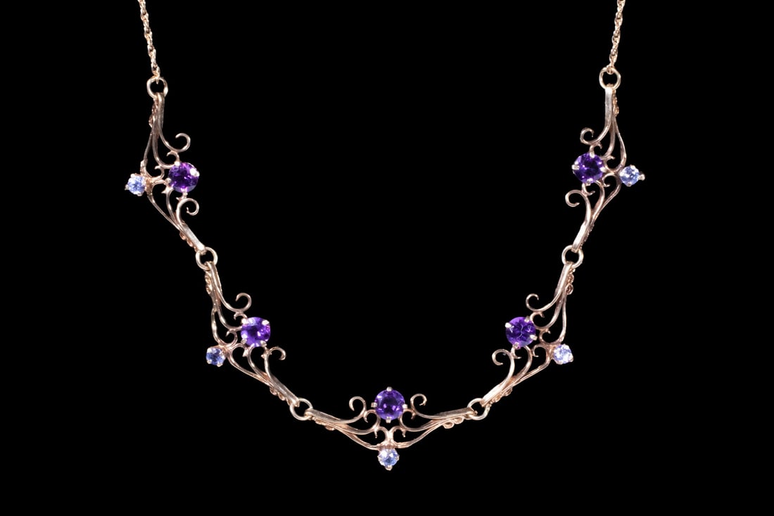 14K GOLD AMETHYST AND IOLITE NECKLACE: 14K GOLD AMETHYST AND IOLITE NECKLACEA 14K gold necklace designed with a decorative frontispiece set with (5) round-cut amethysts and (5) iolites, arranged in a scrolling, openwork motif suggestive of