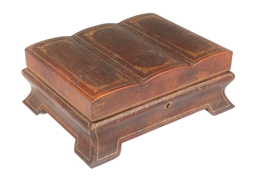 VICTORIAN LEATHER-BOUND TWO-TIER JEWELRY BOX IN FORM OF BOOK: VICTORIAN LEATHER-BOUND TWO-TIER JEWELRY BOX IN FORM OF BOOK A charming 19th-century English jewelry box crafted to resemble a three-volume leather-bound book, opening to reveal a red velvet-lined int
