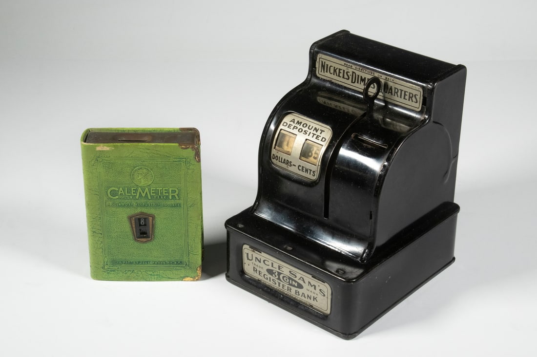 (2) VINTAGE PENNY BANKS: (2) VINTAGE PENNY BANKS Including: Uncle Sam's 3-Coin Register bank, ca. 1920s, by the Durable Toy and Novelty Corporation, in black; and Circa 1920s CaleMeter book form coin bank, a calendar savings