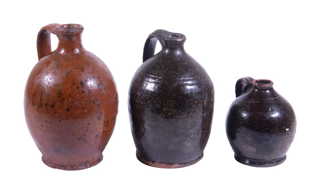 (3) 18TH - EARLY 19TH C. OVOID REDWARE JUGS: (3) 18TH - EARLY 19TH C. OVOID REDWARE JUGS Group of (3) Small Glazed Redware Jars, all with footed base: Dark glazed jug with incised shoulder ring and applied strap handle, 7" high, 4 1/2" diam.,