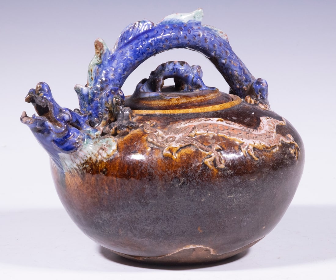 1920S CHINESE POTTERY LARGE TEAPOT: 1920S CHINESE POTTERY LARGE TEAPOT Blue dragon handle and lid knob, white dragon on each side. OS: 9 x 10 x 8 1/2 in. (22.9 x 25.4 x 21.6 cm.)
