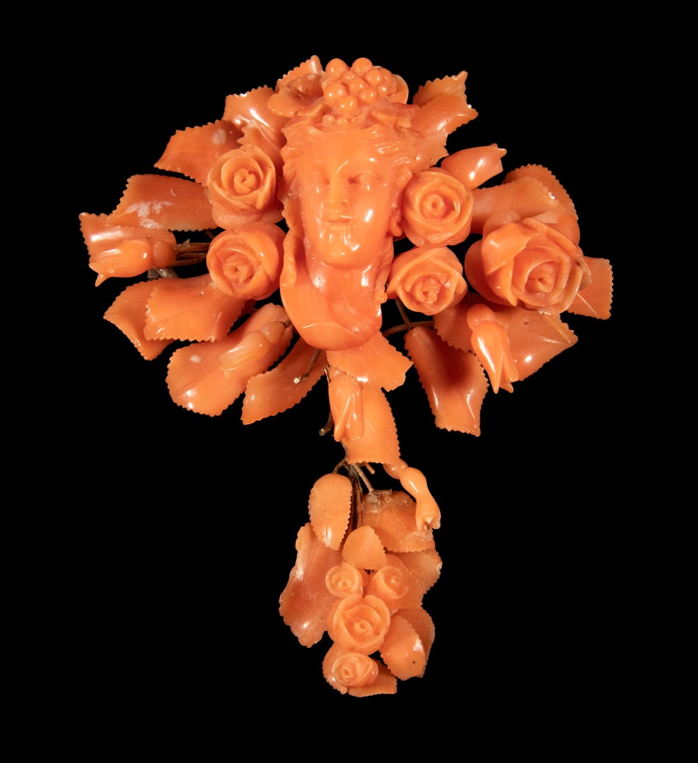 VICTORIAN 14K GOLD CORAL FEMALE BUST AND FLORAL BROOCH: VICTORIAN 14K GOLD CORAL FEMALE BUST AND FLORAL BROOCH A finely carved coral brooch featuring a classical female bust framed by roses and foliage, rendered in a warm salmon-orange hue. The design is f