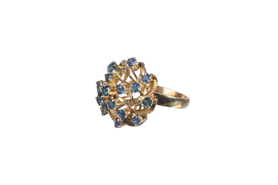 VINTAGE 18K GOLD SAPPHIRE CLUSTER RING: VINTAGE 18K GOLD SAPPHIRE CLUSTER RING An 18K gold ring in a bold, domed cluster design, set with (17) round-cut sapphires measuring approximately 3.16 mm each. The sapphires display a medium to deep 