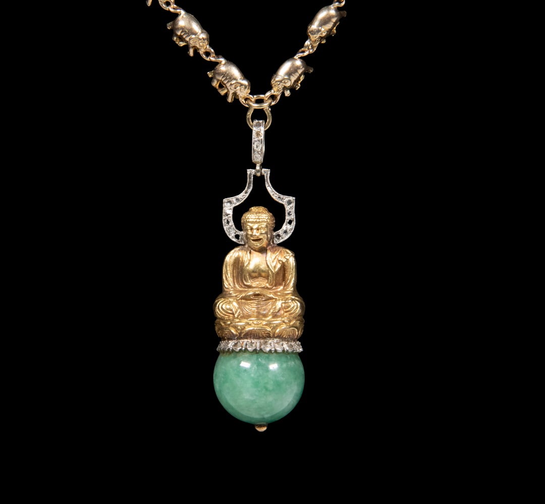 14K GOLD JADE AND DIAMOND BUDDHA PENDANT NECKLACE: 14K GOLD JADE AND DIAMOND BUDDHA PENDANT NECKLACE A 14K gold necklace composed of articulated elephant-form links, suspending a seated Buddha pendant executed in yellow gold above a polished green jad