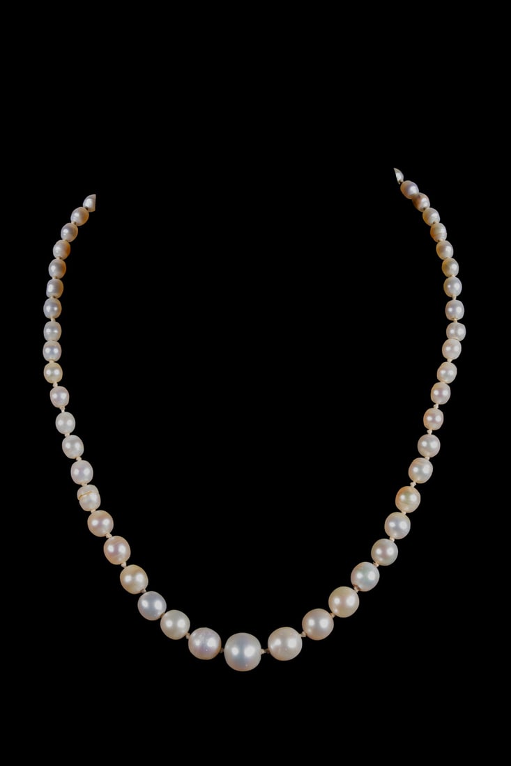 RAYMOND YARD 18K GOLD NATURAL PEARL NECKLACE WITH DIAMOND AND EMERALD CLASP: RAYMOND YARD 18K GOLD NATURAL PEARL NECKLACE WITH DIAMOND AND EMERALD CLASP A graduated natural pearl necklace composed of (57) near-round and oval light cream natural pearls, ranging from 3.91 x 33.4