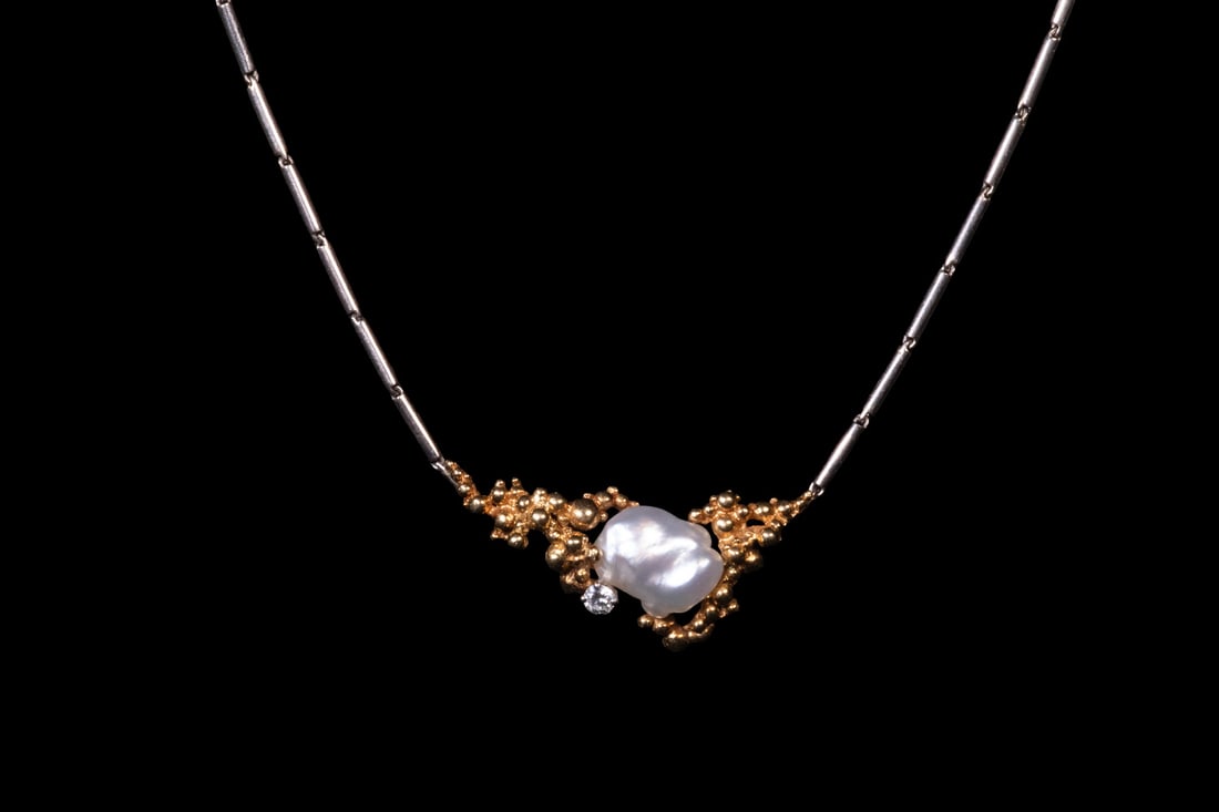 GILBERT ALBERT 18K GOLD DIAMOND AND BAROQUE PEARL NECKLACE: GILBERT ALBERT 18K GOLD DIAMOND AND BAROQUE PEARL NECKLACE An 18K two-tone gold necklace, dating to the 1980s, composed of articulated tubular bar links suspending an organic nugget-form pendant cente