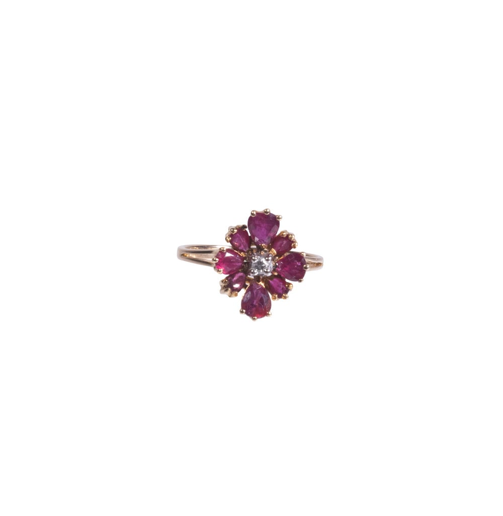 VINTAGE 14K GOLD RUBY AND DIAMOND CLUSTER RING: VINTAGE 14K GOLD RUBY AND DIAMOND CLUSTER RING A 14K yellow gold ring featuring a floral cluster design centered with a round-cut diamond, surrounded by (8) pear-cut rubies of vibrant dark rose-red hu