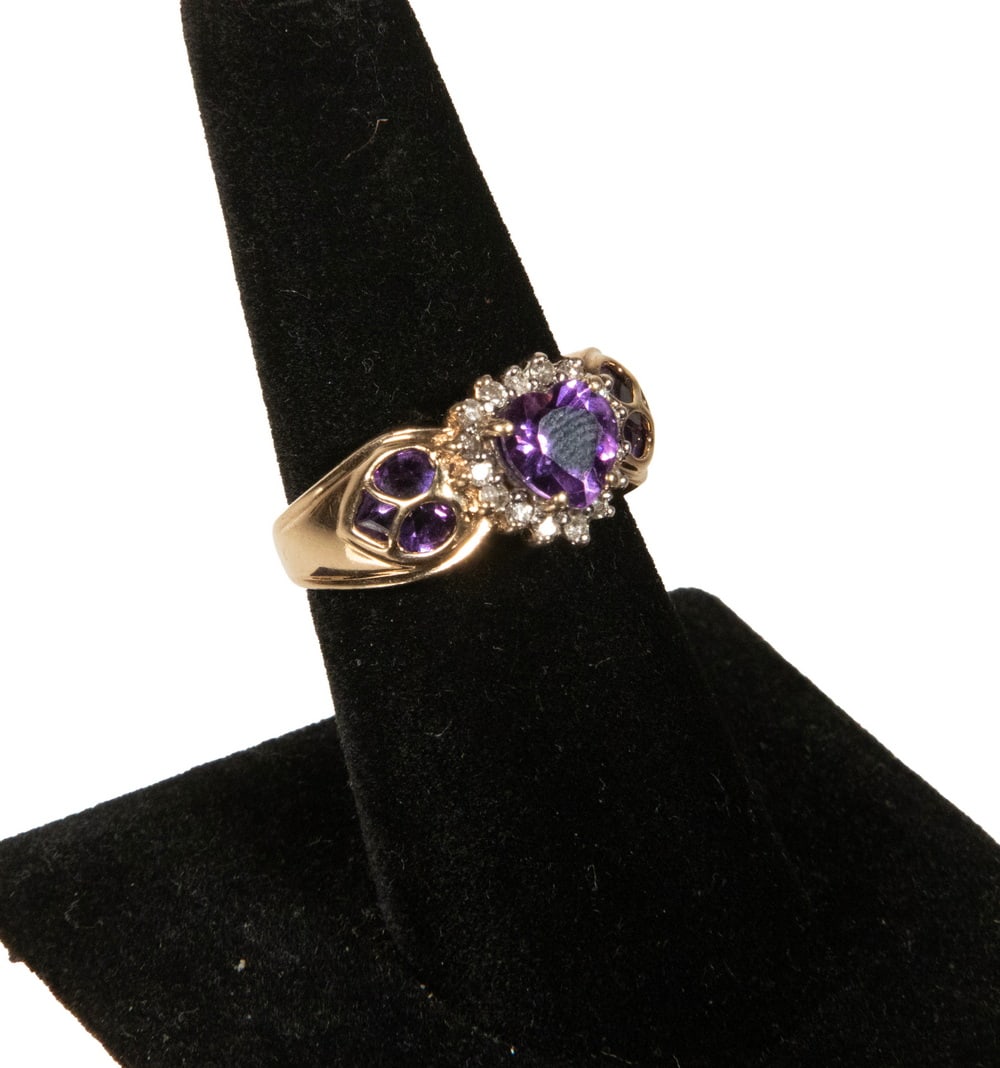 14K GOLD AMETHYST AND DIAMOND HEART RING: 14K GOLD AMETHYST AND DIAMOND HEART RING A 14K gold ring featuring a heart-cut amethyst measuring approximately 6.93 x 7.00 mm, displaying a rich medium-to-deep purple hue, surrounded by (16) round di