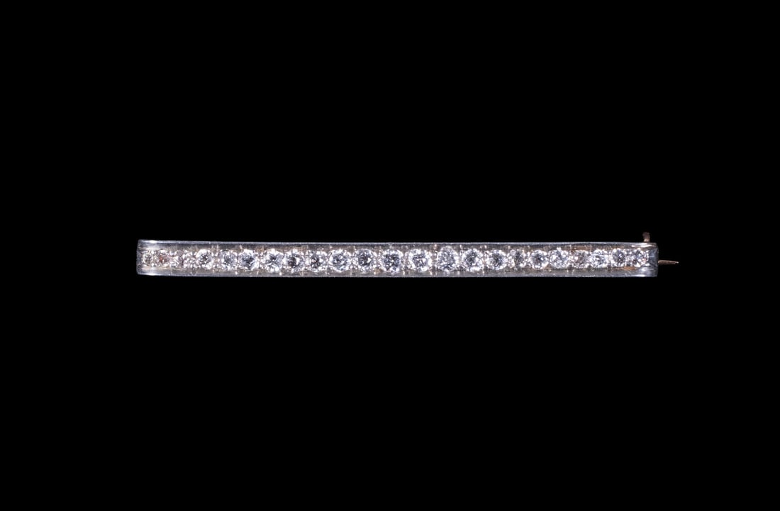 ART DECO 10K GOLD AND DIAMOND BAR BROOCH: ART DECO 10K GOLD AND DIAMOND BAR BROOCH Set with (23) round old-cut diamonds in a graduated arrangement, the diamonds mounted in a white gold top over a yellow gold frame. Completed with a lever safe