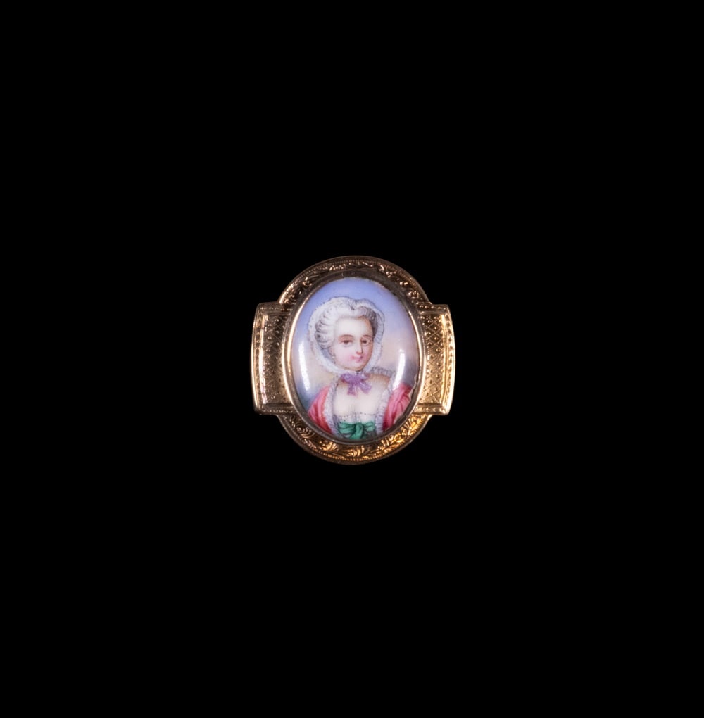 VICTORIAN 14K GOLD ENAMEL PORTRAIT BROOCH, C.1880: VICTORIAN 14K GOLD ENAMEL PORTRAIT BROOCH, C.1880 A 14K yellow gold brooch featuring a finely painted enamel portrait of an 18th-century lady wearing a lace bonnet and rose-colored gown. The oval mini