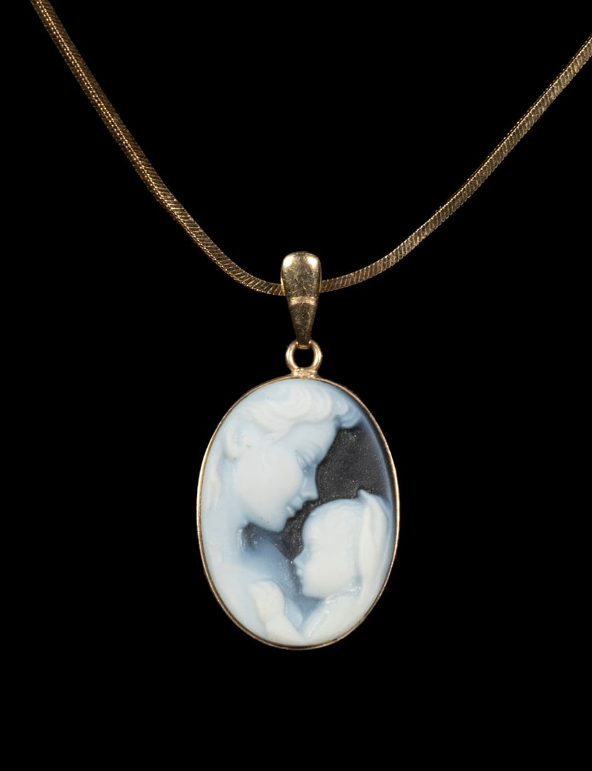 14K GOLD ONYX CAMEO PENDANT NECKLACE: 14K GOLD ONYX CAMEO PENDANT NECKLACE A 14K yellow gold pendant featuring an oval onyx cameo, carved in relief depicting a mother and child in profile. The white carving contrasts against a darker grou
