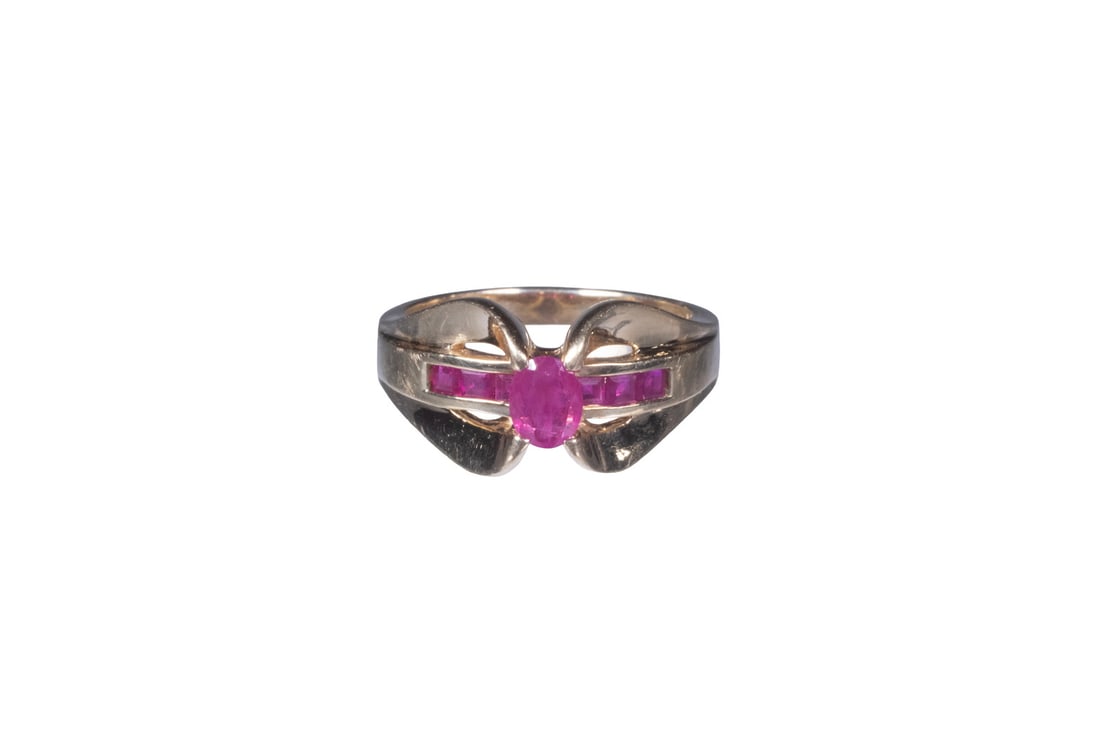 VINTAGE 14K GOLD AND RUBY RING: VINTAGE 14K GOLD AND RUBY RING A 14K gold ring set with a central oval-cut ruby measuring approximately 5.07 x 3.96 mm, above a lower tier set with (7) square-cut rubies in a channel setting. The ston