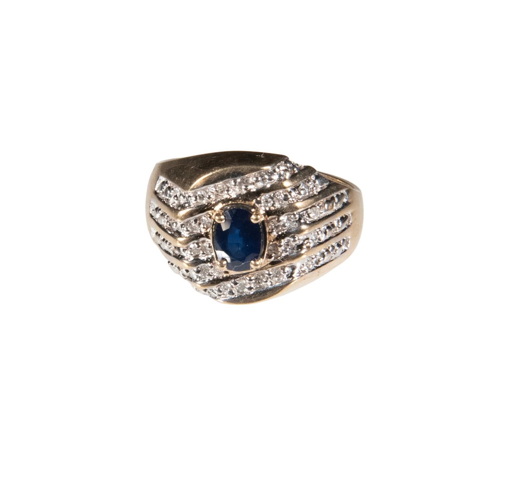 10K GOLD SAPPHIRE AND DIAMOND RING: 10K GOLD SAPPHIRE AND DIAMOND RING A 10K gold ring set with an oval-cut blue sapphire, 7 mm X 5.5 mm, accented by multiple rows of small round diamonds in a bold, tiered design. The wide band features