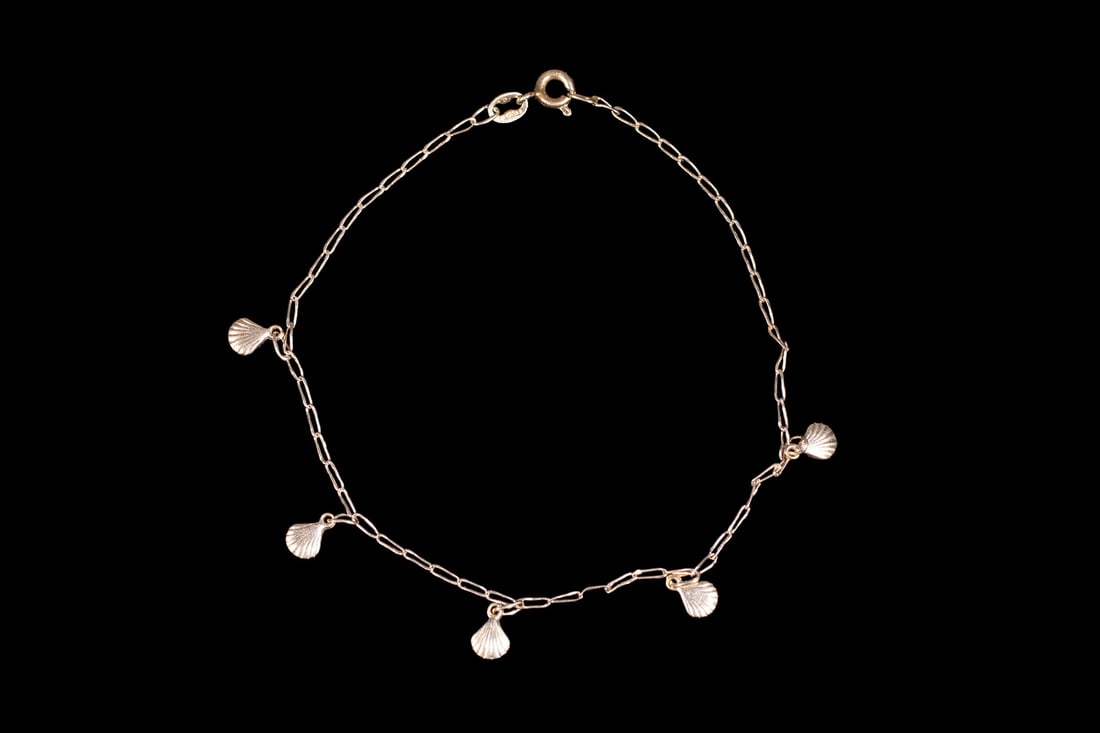ITALIAN 14K GOLD SHELL CHARM BRACELET: ITALIAN 14K GOLD SHELL CHARM BRACELET An Italian 14K gold bracelet featuring (5) small shell-form charms suspended from a fine link chain. Each charm is detailed with radiating lines to simulate