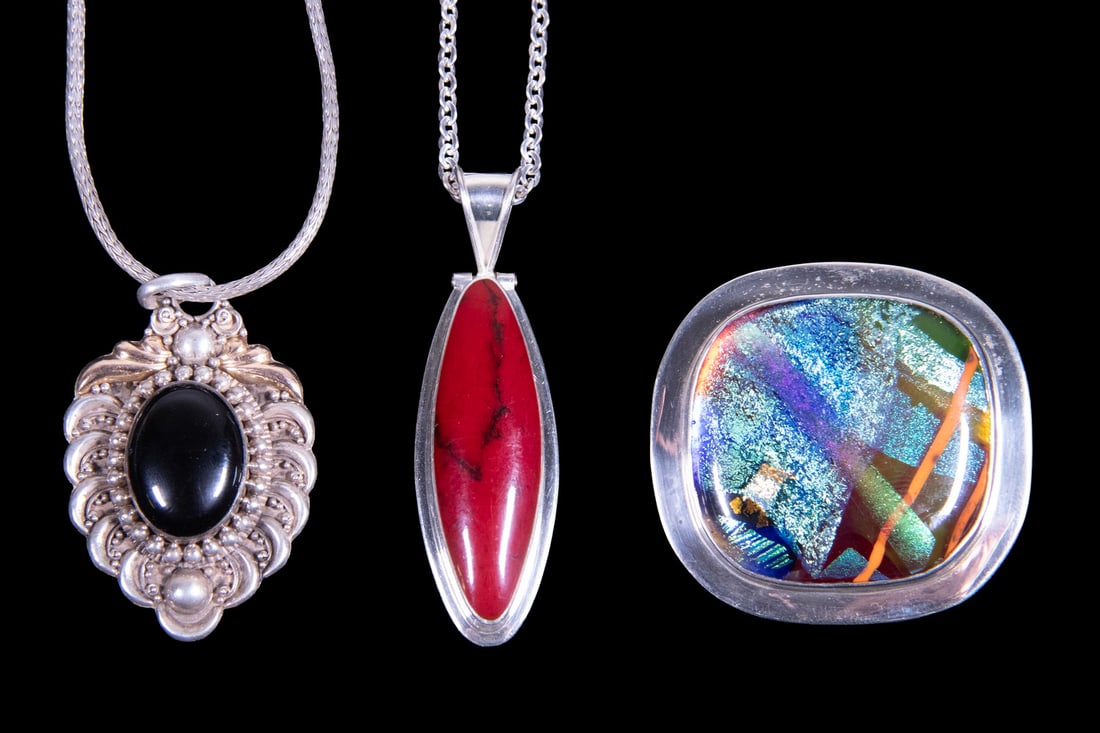 (3) STERLING SILVER AND HARDSTONE JEWELRY ITEMS: (3) STERLING SILVER AND HARDSTONE JEWELRY ITEMS A group including two pendant necklaces and one brooch, each mounted in sterling silver. One pendant set with an oval onyx within an ornate frame; anoth