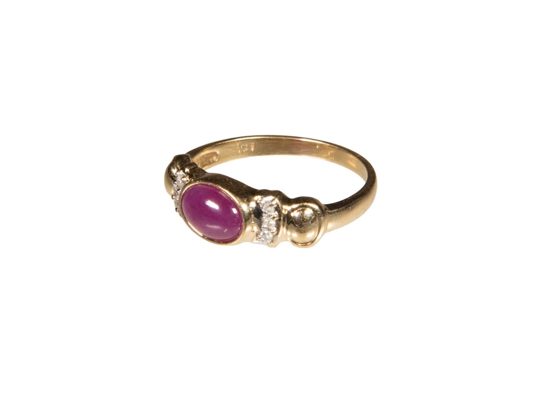 14K GOLD RUBY AND DIAMOND RING: 14K GOLD RUBY AND DIAMOND RING Centering an oval cabochon ruby measuring approximately 7.53 x 5.58 mm, flanked on each side by (3) round diamond melee accents. The ruby displays a rich purplish-red to