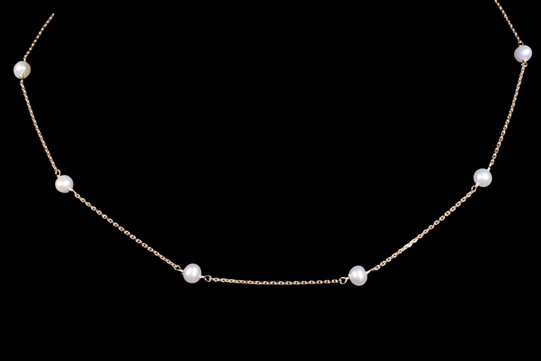 14K GOLD AND PEARL STATION NECKLACE: 14K GOLD AND PEARL STATION NECKLACE A 14K gold necklace featuring (8) evenly spaced round pearls, each measuring approximately 4.5 mm. The pearls are set along a fine link chain in a classic station