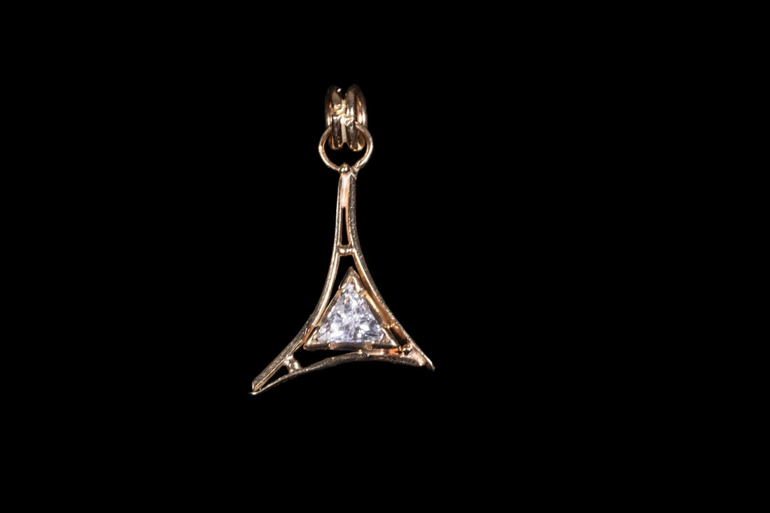 14K GOLD AND CUBIC ZIRCONIA PENDANT: 14K GOLD AND CUBIC ZIRCONIA PENDANT A 14K gold pendant featuring an openwork triangular design, set with a single trillion-cut cubic zirconia at the center. The geometric frame is formed with tapered 