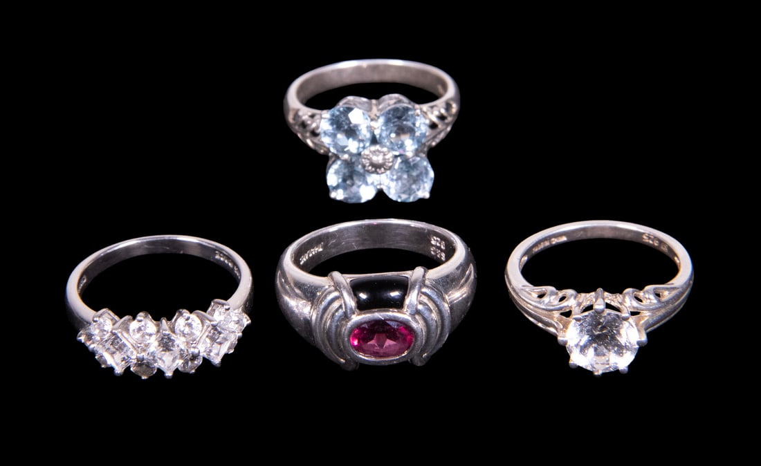 (4) VINTAGE STERLING SILVER TOPAZ, AND GARNET RINGS: (4) VINTAGE STERLING SILVER TOPAZ, AND GARNET RINGS A group of four sterling silver rings comprising: one set with four round blue topaz stones, each measuring approximately 6.03 mm, arranged in a flo