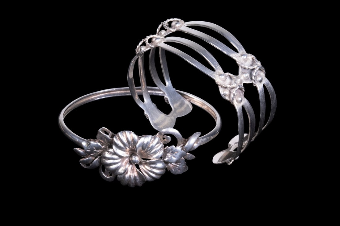 (2) VINTAGE STERLING SILVER CUFF BRACELETS: (2) VINTAGE STERLING SILVER CUFF BRACELETS Including two vintage sterling silver cuff bracelets, one designed with a floral repouss?-style centerpiece and openwork floral gallery, the other of split-b